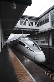 a silver bullet train pulling into a train station
