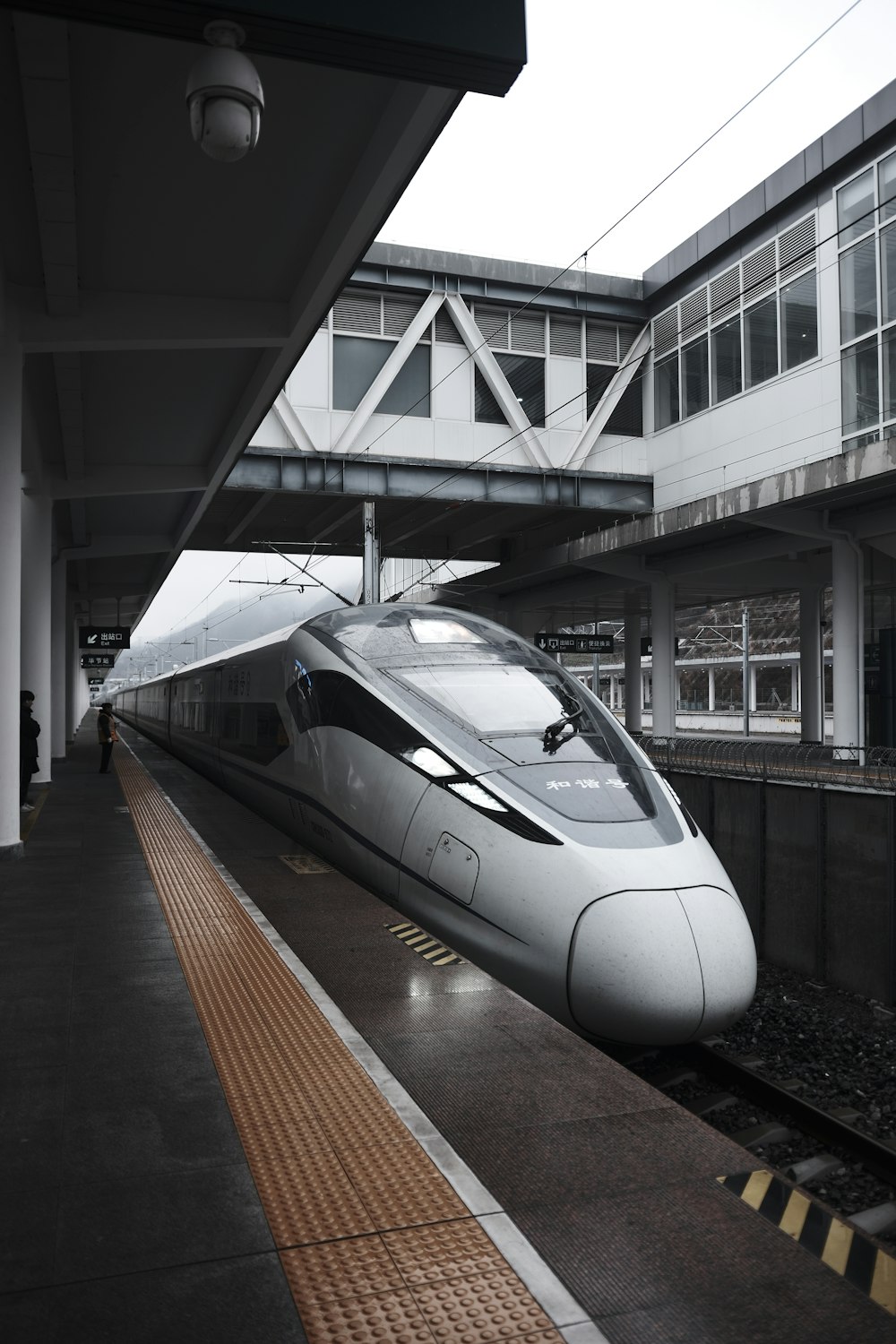 a silver bullet train pulling into a train station