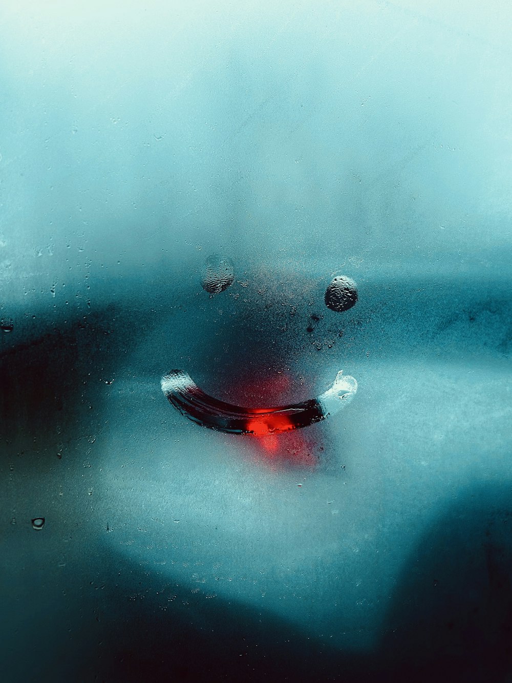 un objet rouge assis sur une fenêtre humide