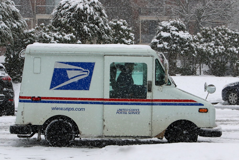 a mail truck driving down a snow covered street