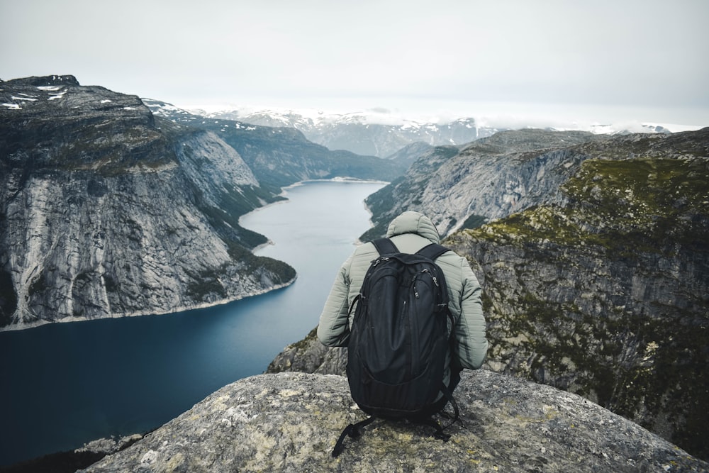 a person with a backpack sitting on top of a mountain