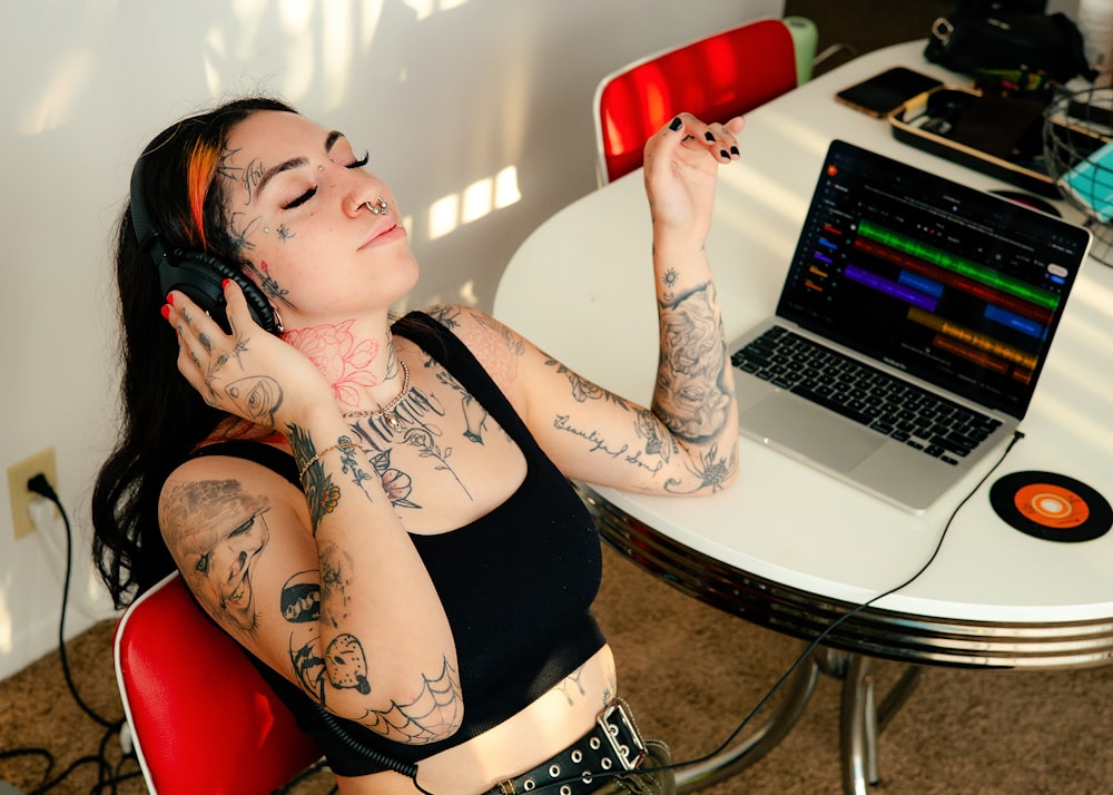a woman with tattoos sitting in front of a laptop