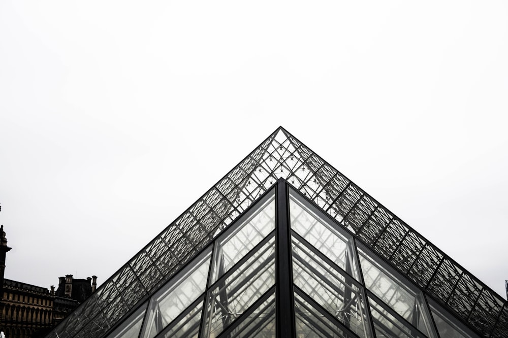 a very tall glass pyramid with a clock tower in the background