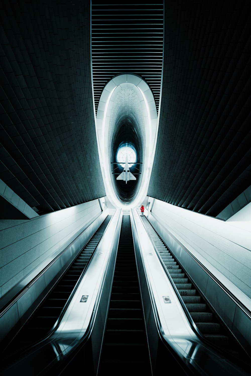 an escalator going through a tunnel with a light at the end