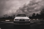 a white car parked in a parking lot under a cloudy sky