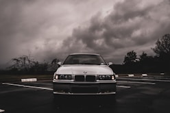 a white car parked in a parking lot under a cloudy sky
