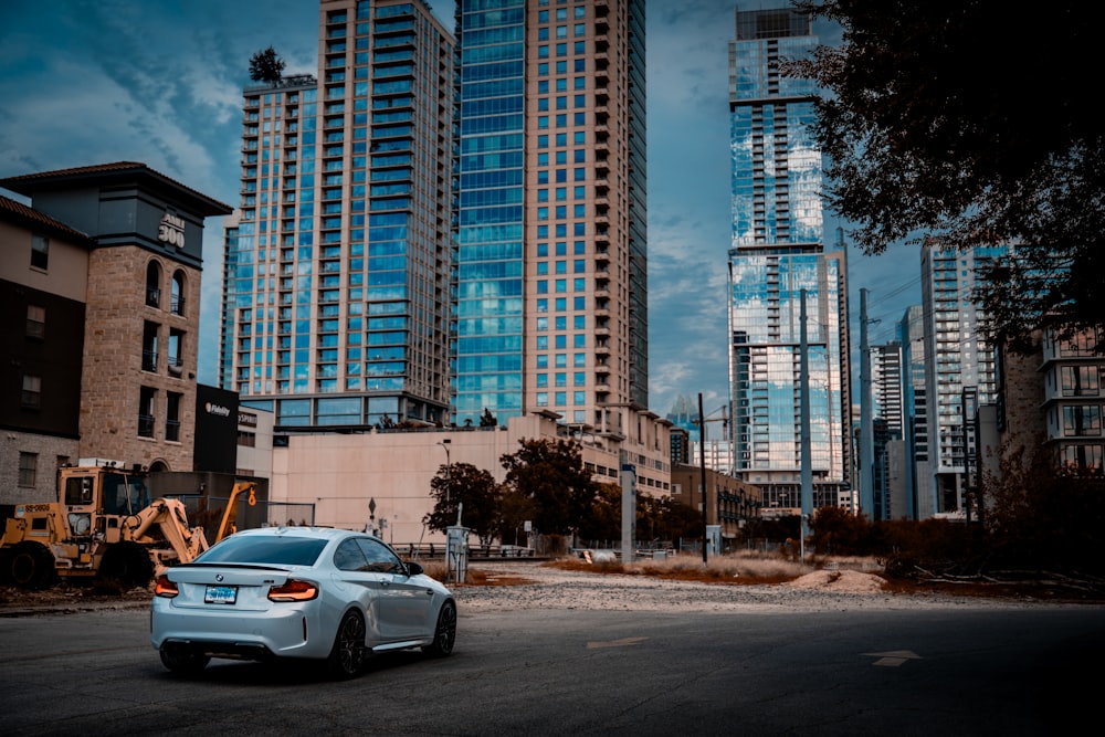 a car parked on the side of a road in front of tall buildings