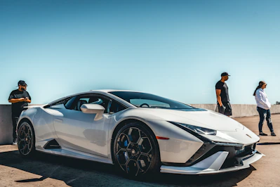 two men standing next to a white sports car