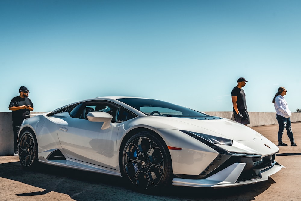 two men standing next to a white sports car