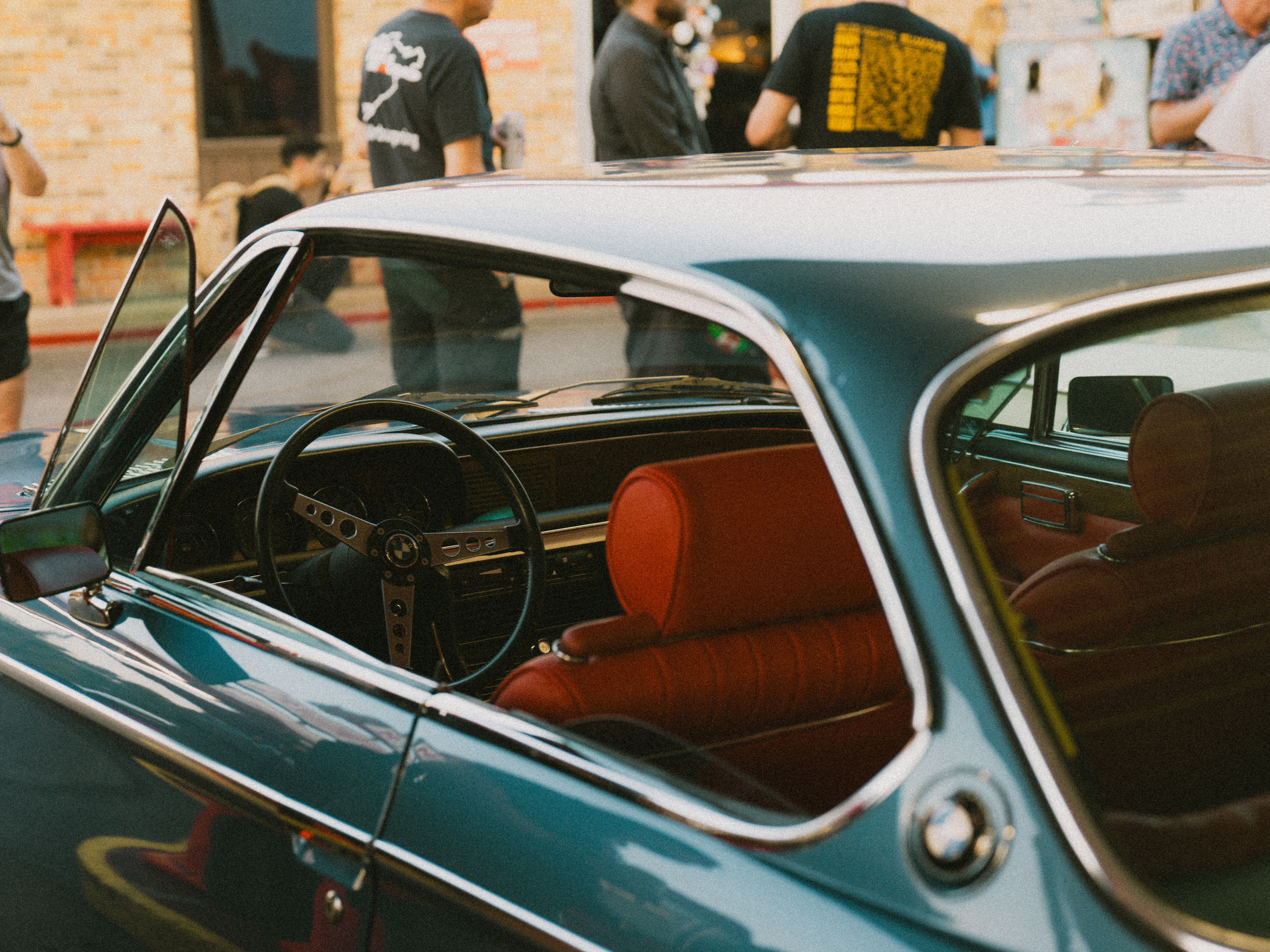 a group of people standing around a parked car
