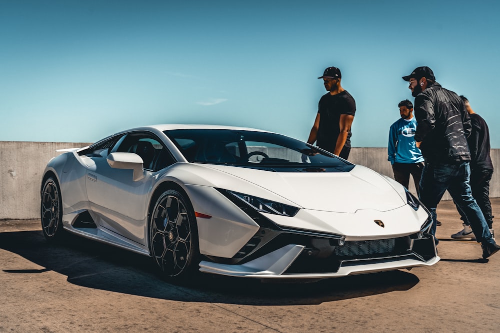 two men standing next to a white sports car