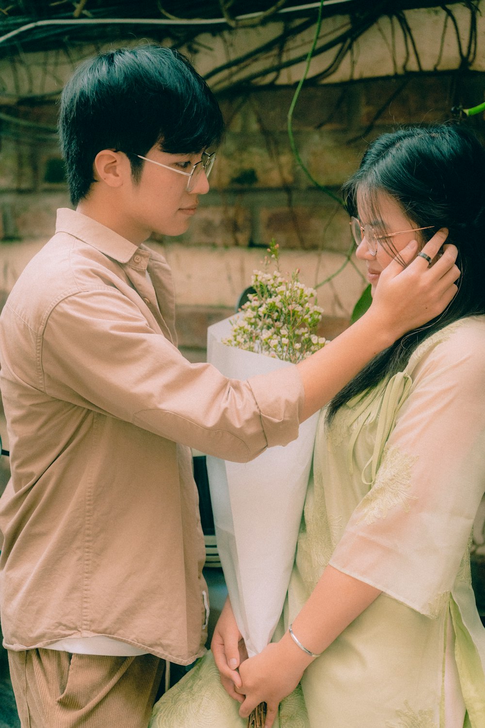 a man putting a flower pot on a woman's shoulder