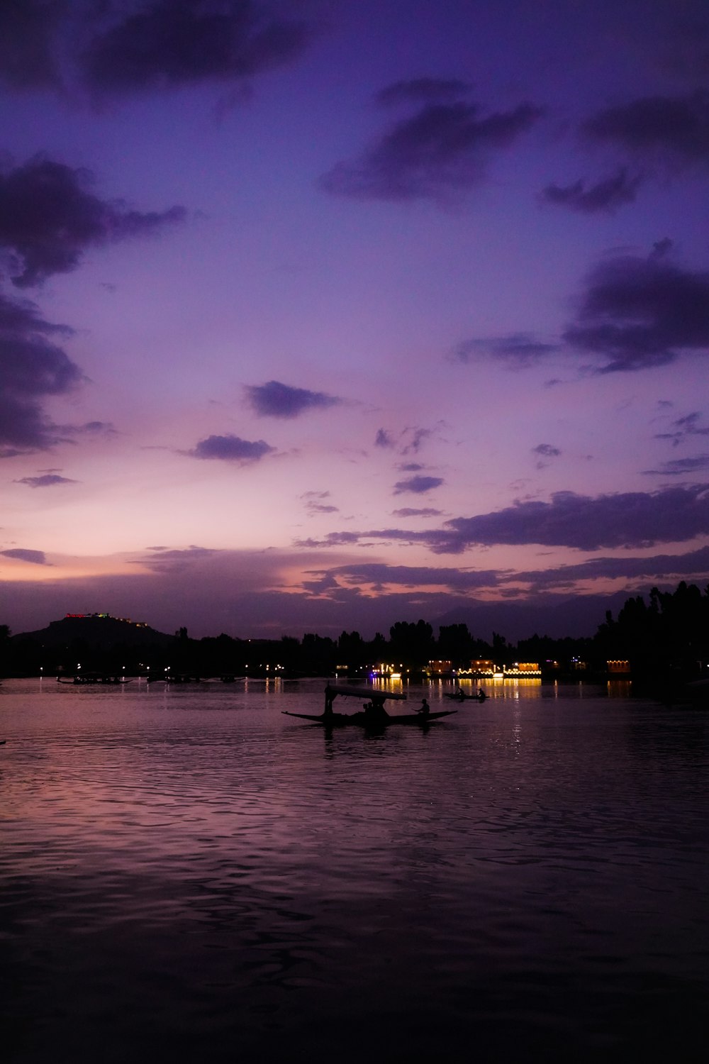 a boat floating on top of a lake under a purple sky