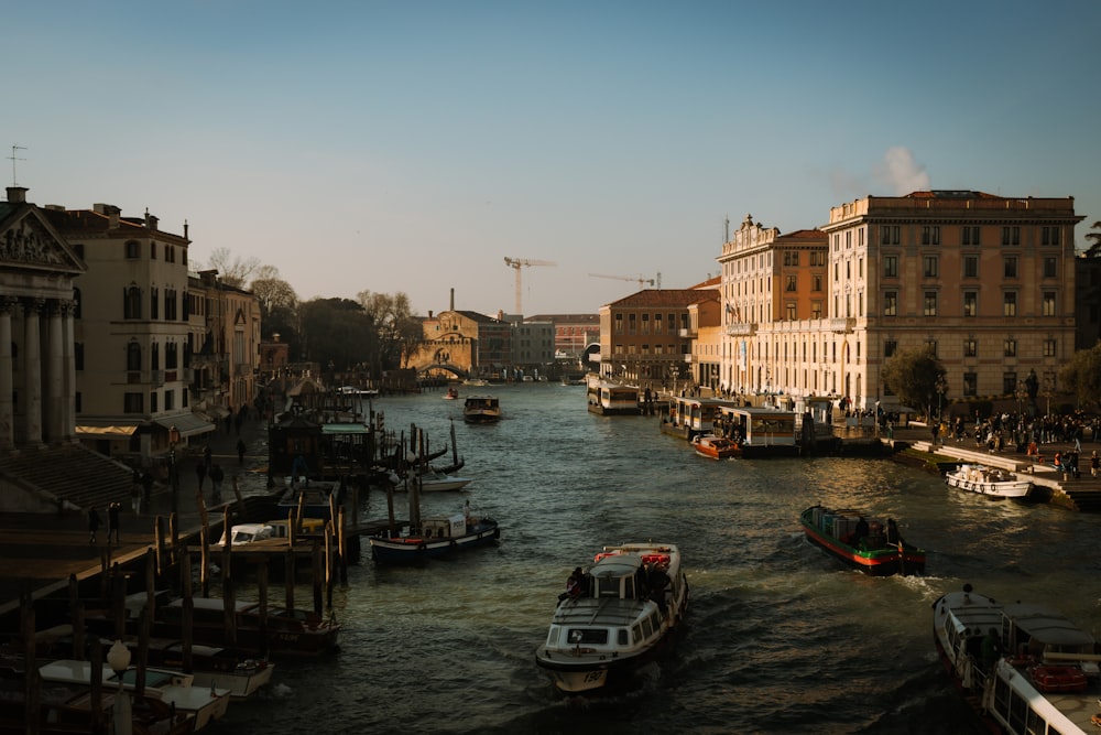 a group of boats floating down a river next to tall buildings