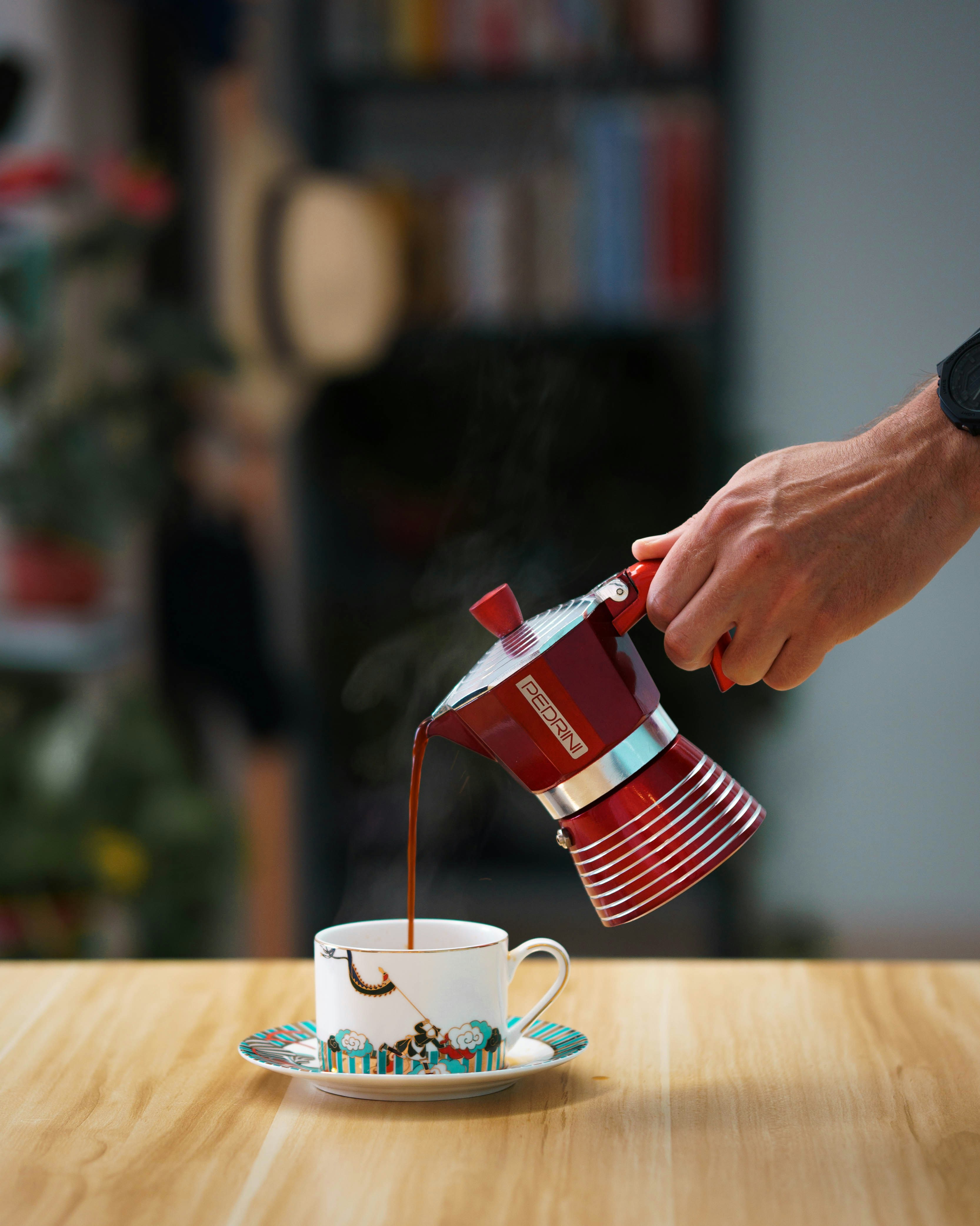 a person pouring coffee into a cup on a table