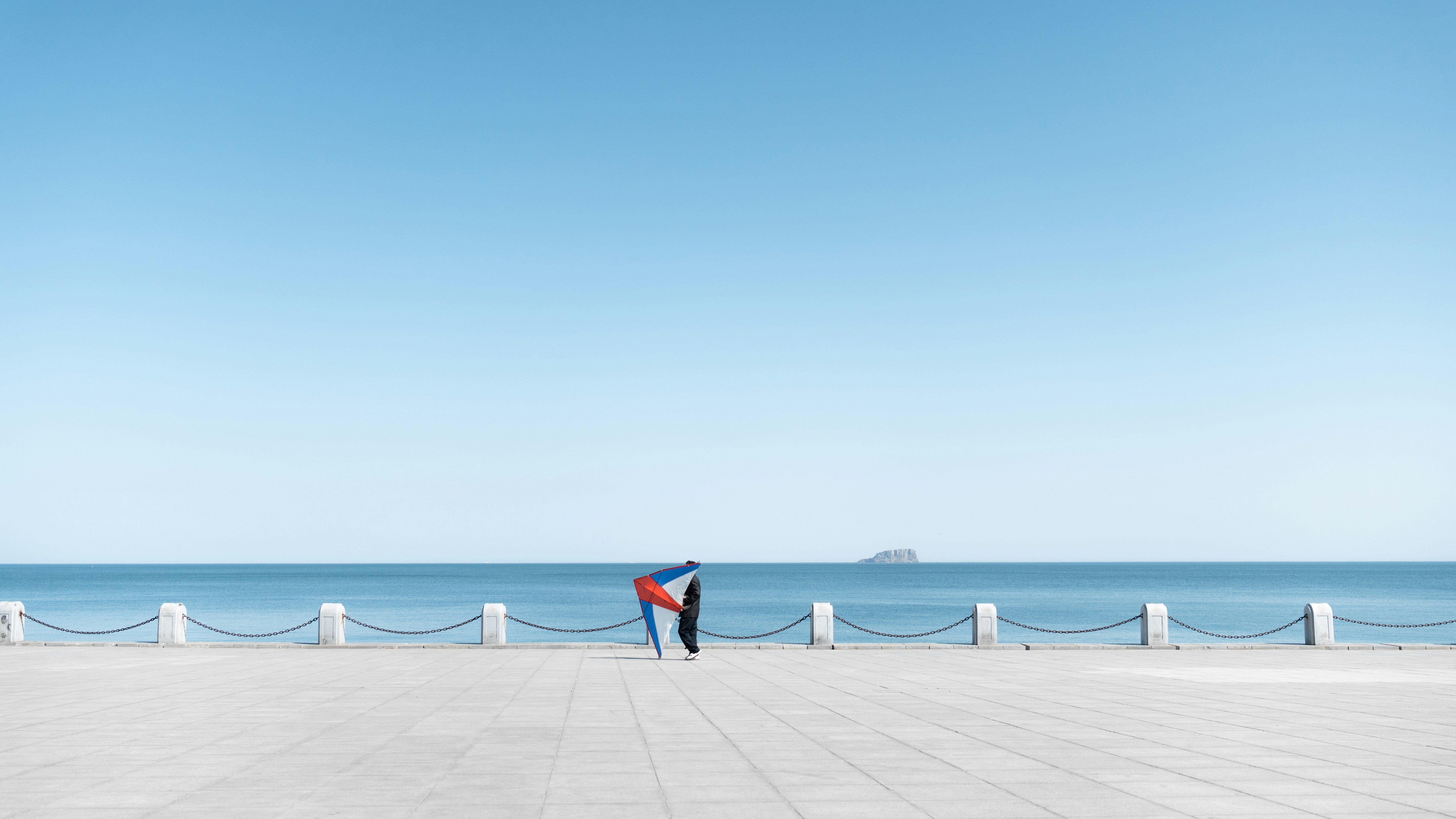 a man standing on a sidewalk next to the ocean