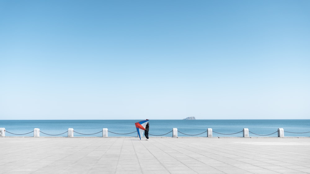 a man standing on a sidewalk next to the ocean