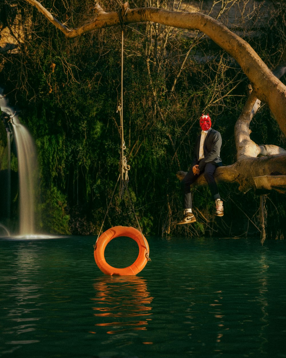 a man sitting on a tree branch next to a body of water