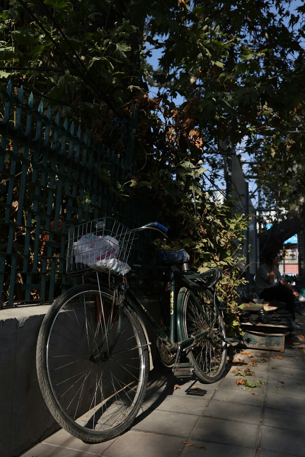 a bicycle parked next to a green fence
