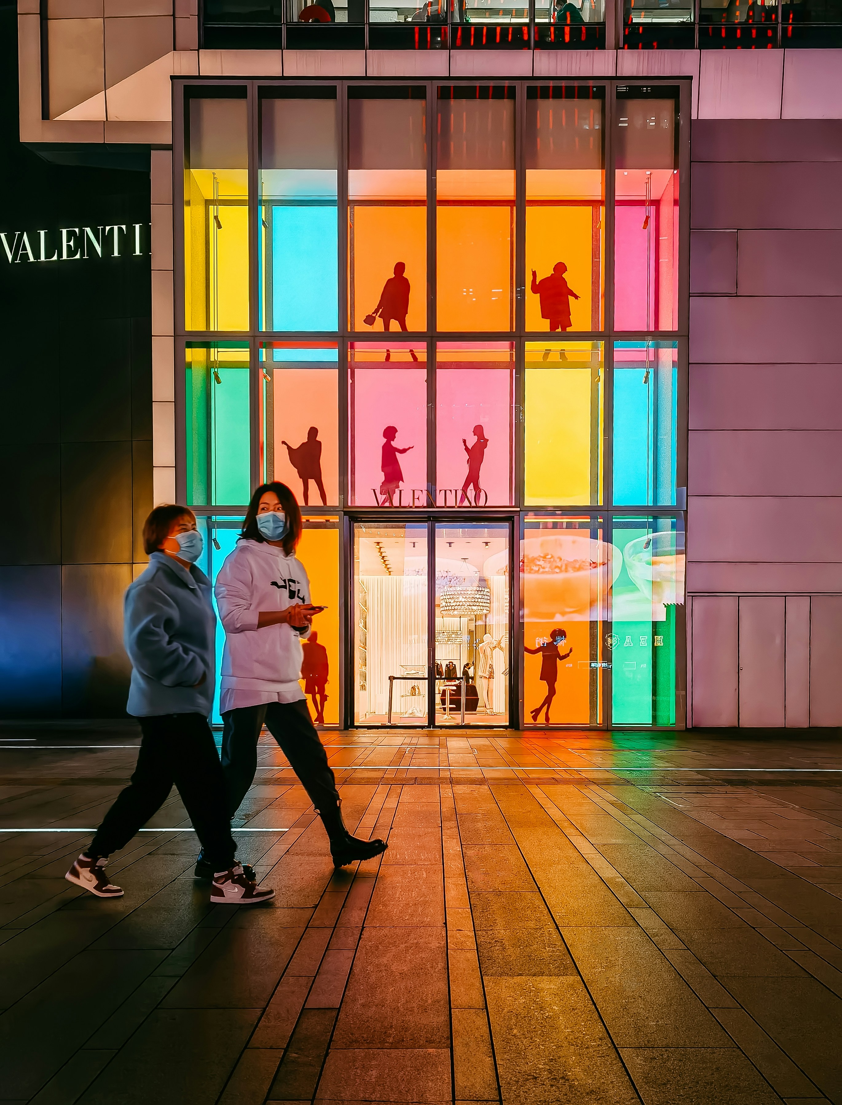 a couple of people walking down a sidewalk near a building