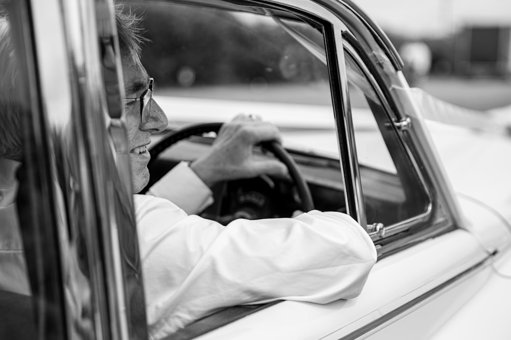 a man sitting in a car with his hand on the steering wheel