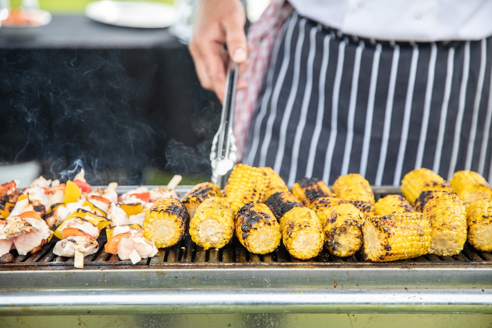 a person grilling corn on the cob on a grill