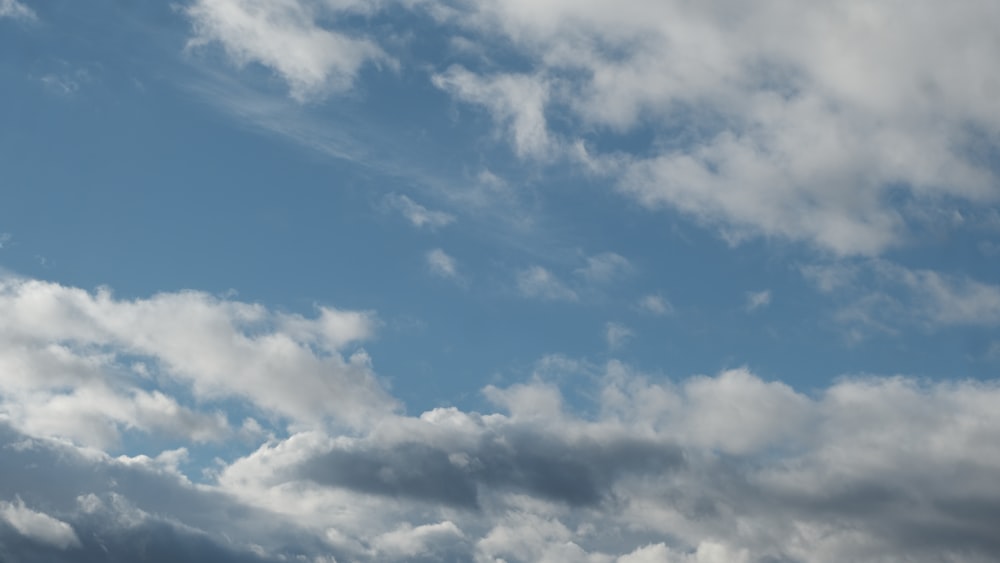 a plane flying through a cloudy blue sky