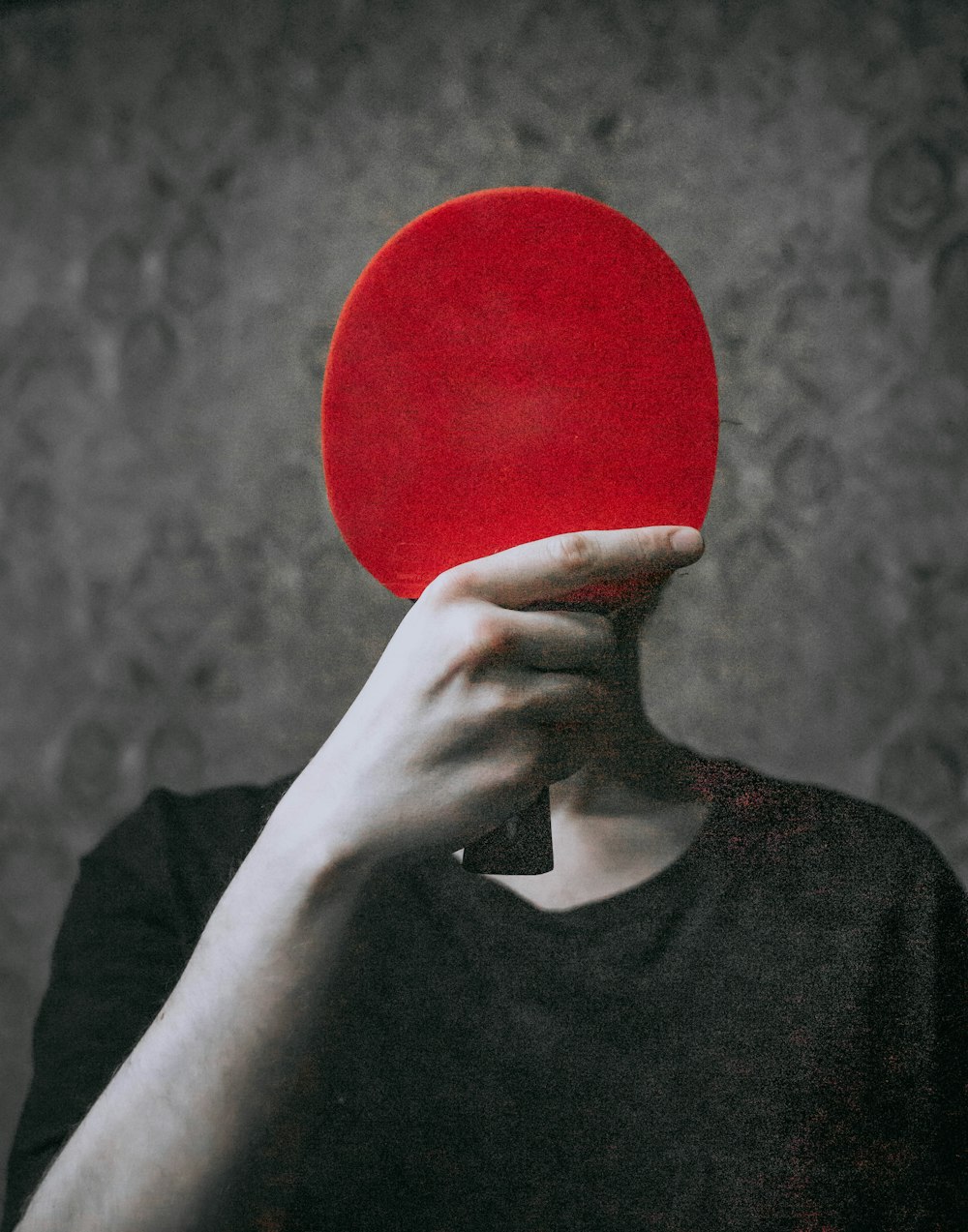 a person holding a red ping pong paddle up to their face