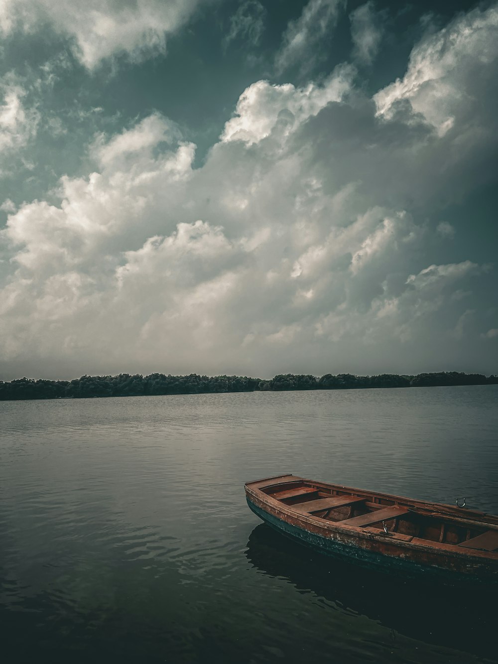 a boat floating on top of a lake under a cloudy sky