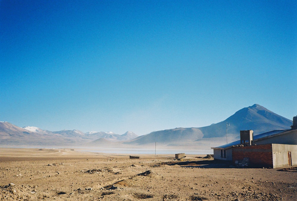 a building in the middle of a desert with mountains in the background