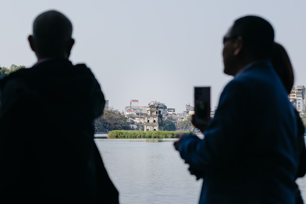 a couple of people standing next to a body of water