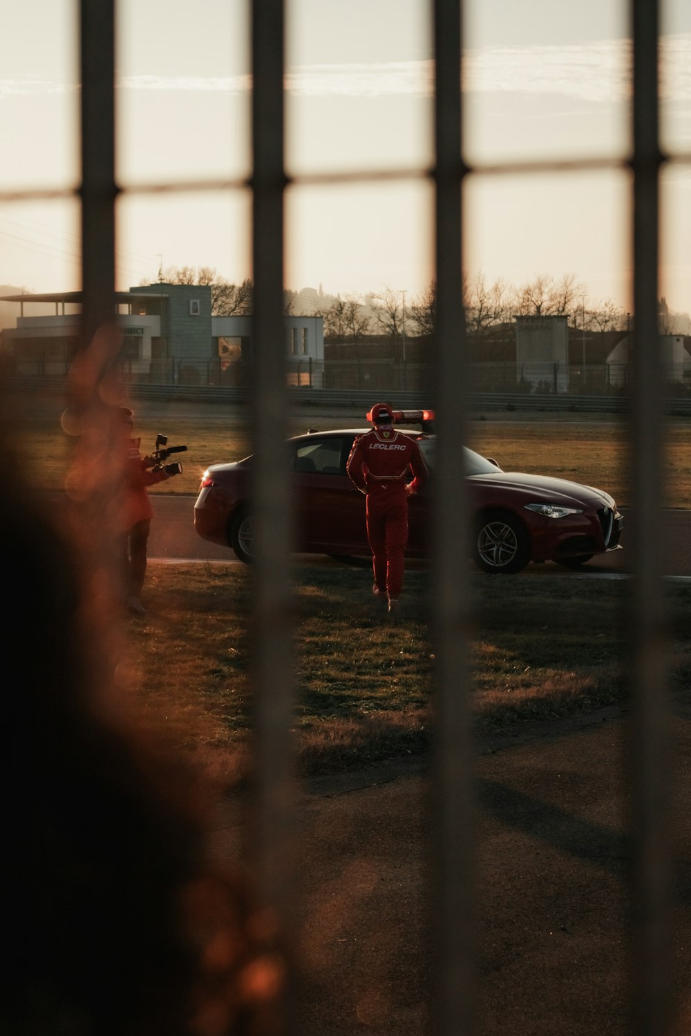 una persona in un abito rosso in piedi accanto a un'auto rossa