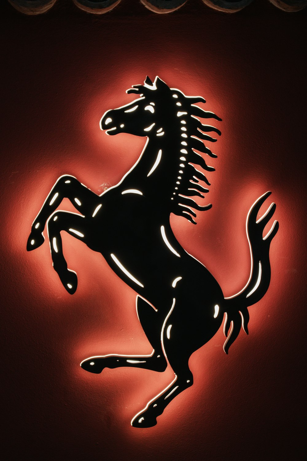 Um logotipo preto e vermelho da Ferrari em uma parede vermelha