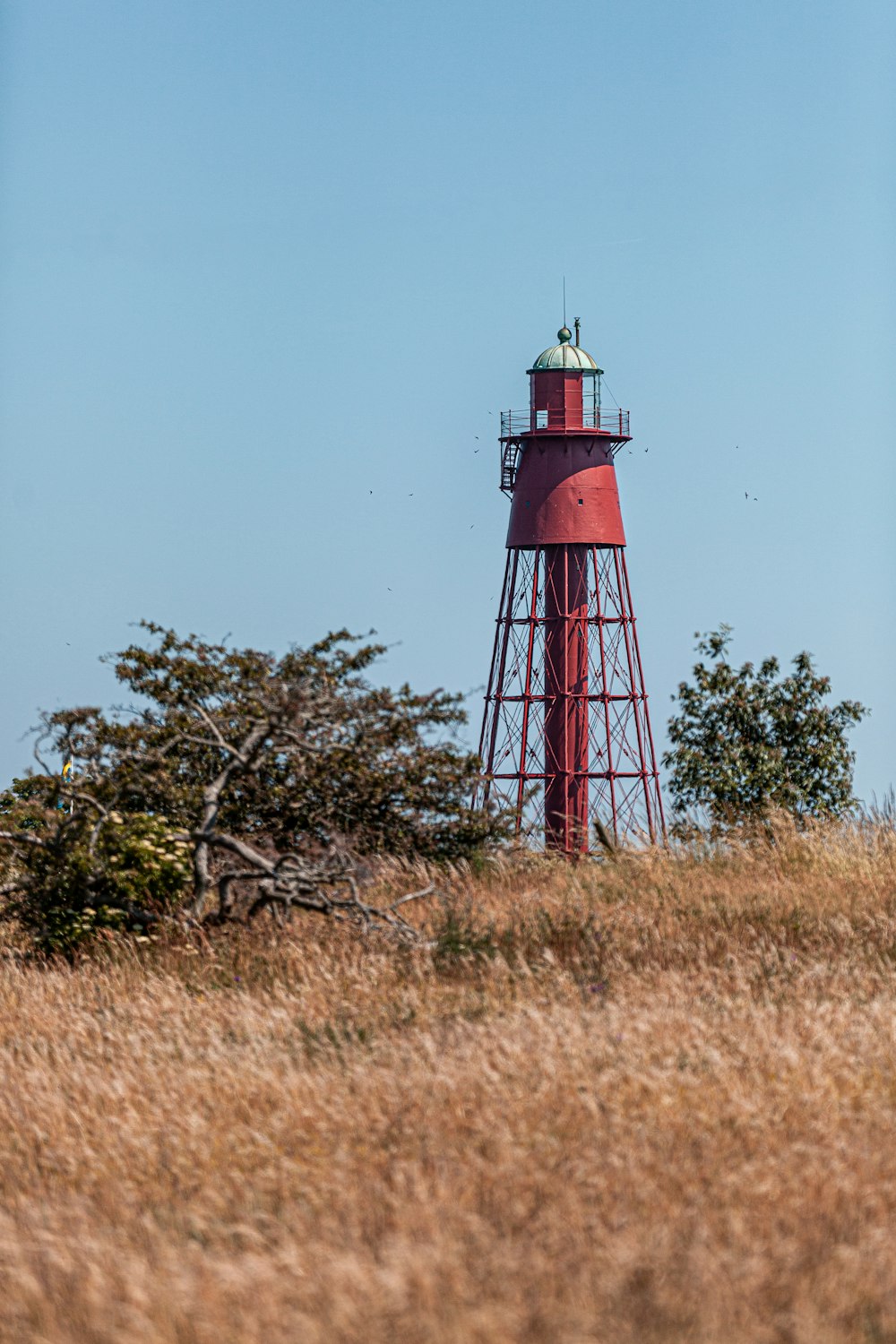 a red light house sitting on top of a hill
