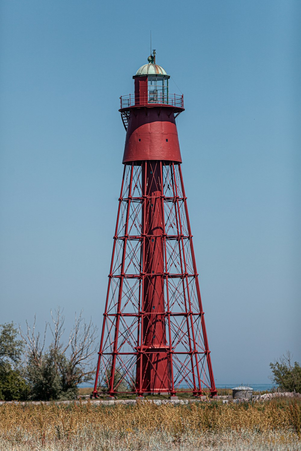 a red light house sitting in the middle of a field