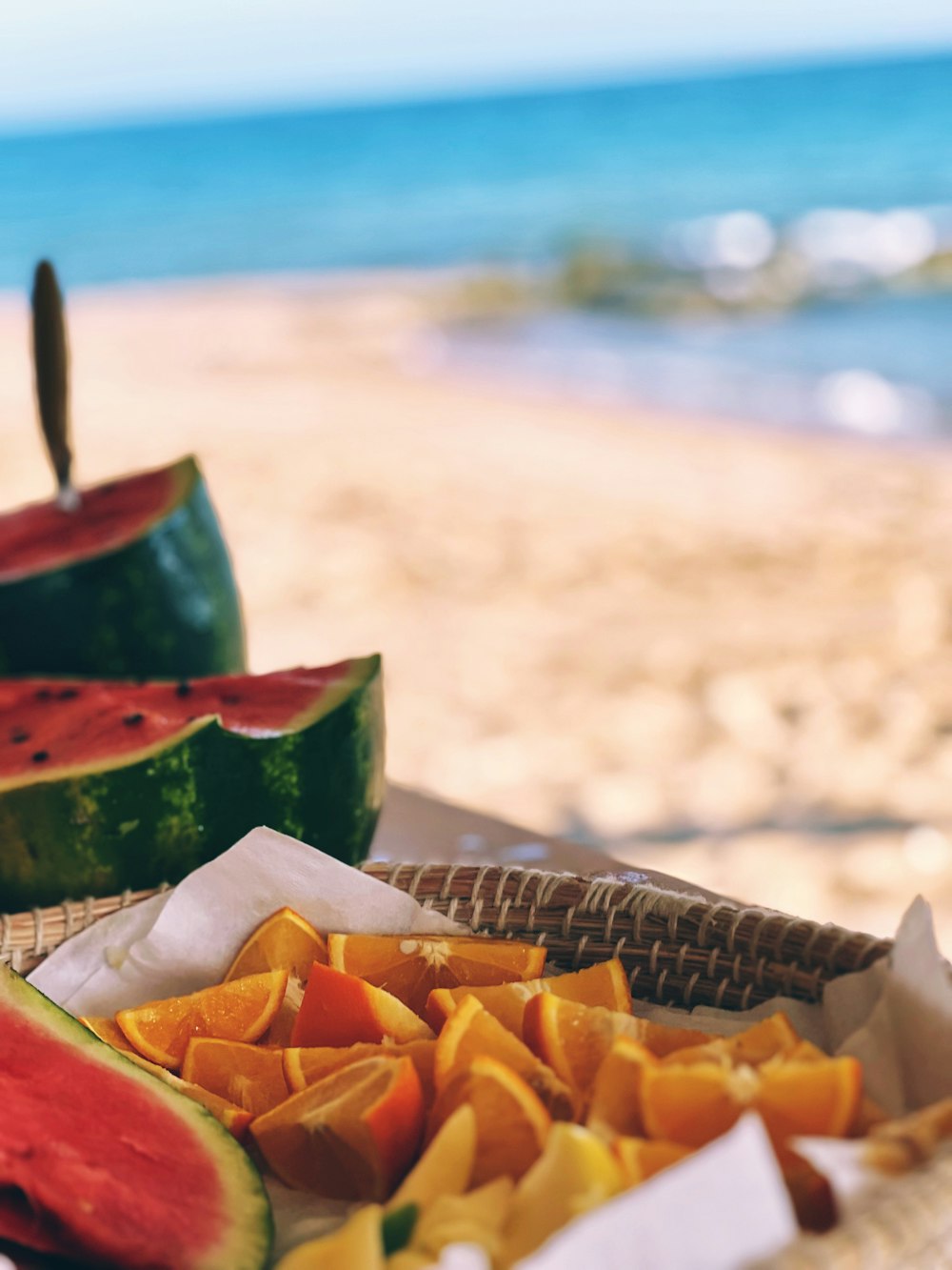 a plate of watermelon and melon slices on a beach