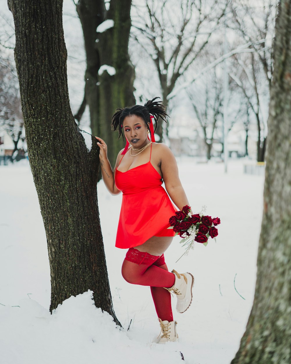 a woman in a red dress standing next to a tree
