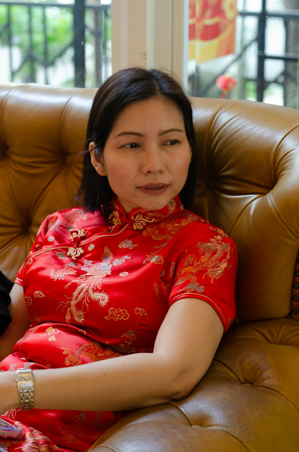 a woman in a red dress sitting on a brown chair