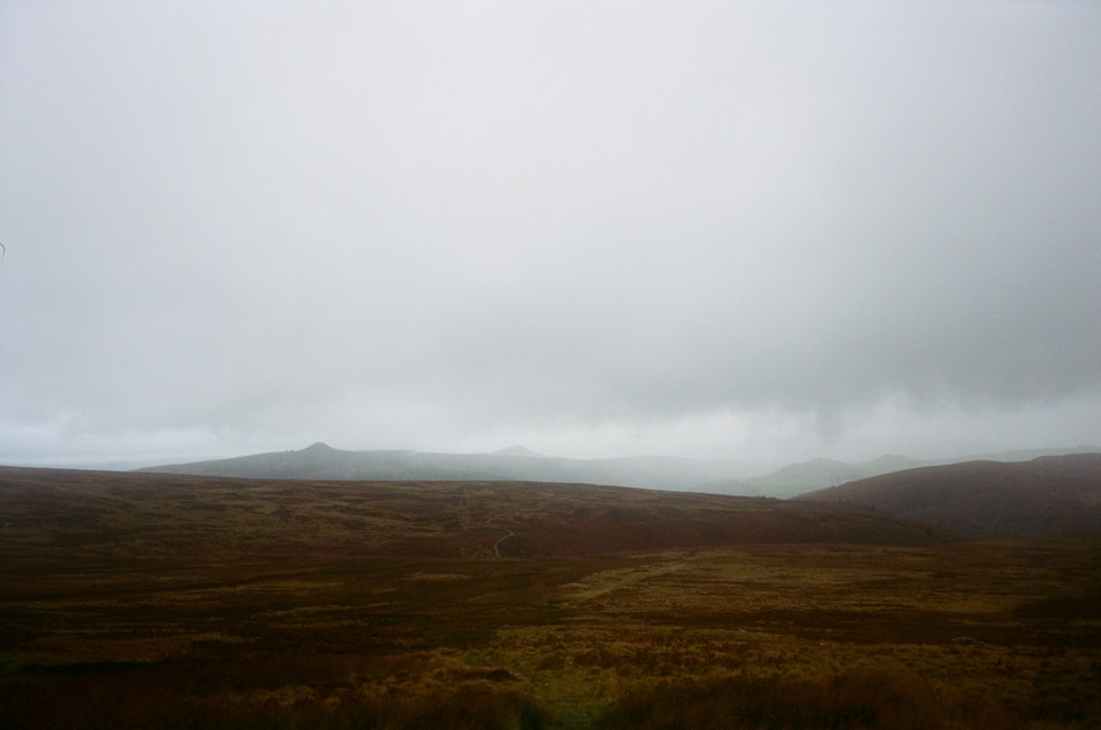 a grassy field with a hill in the distance