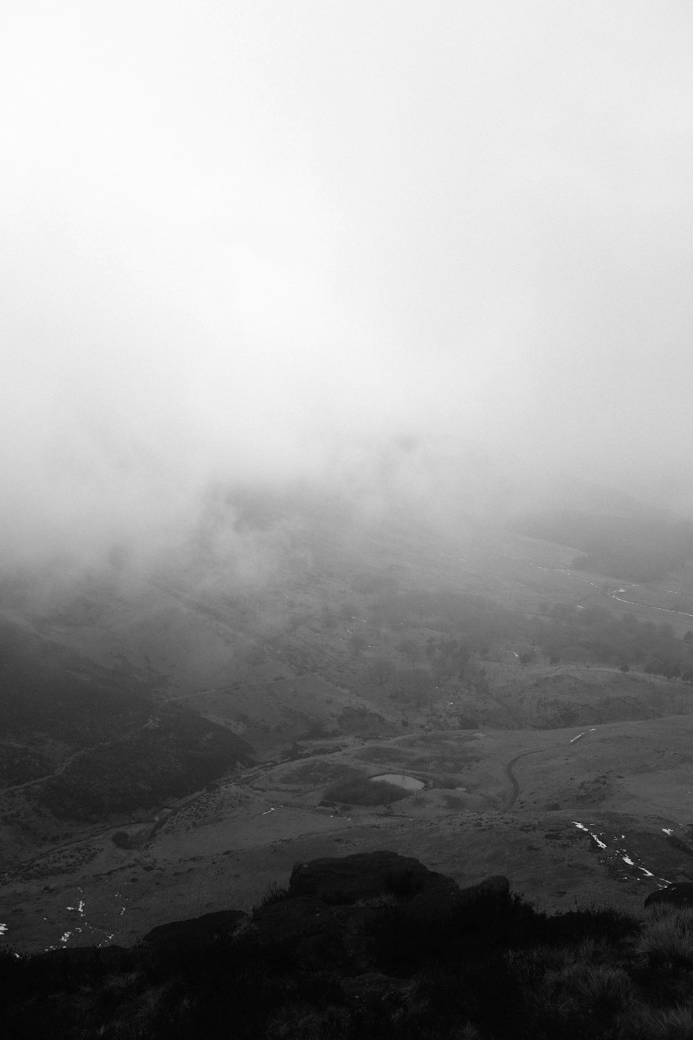 a black and white photo of a foggy mountain