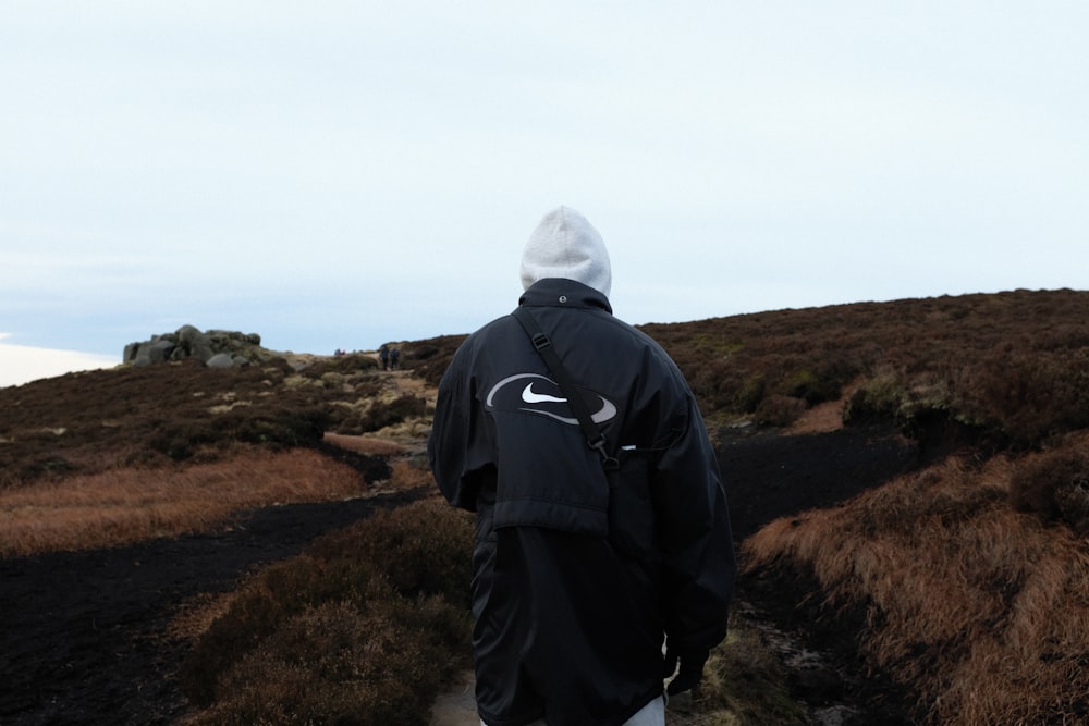 a man in a black jacket is walking on a path