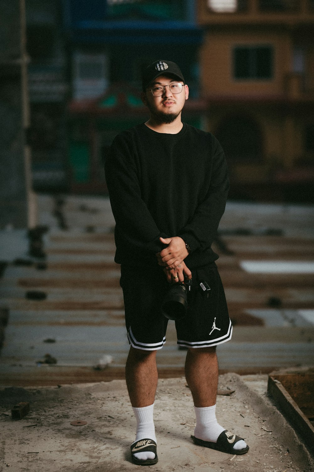 a man in a black shirt and shorts standing on a sidewalk