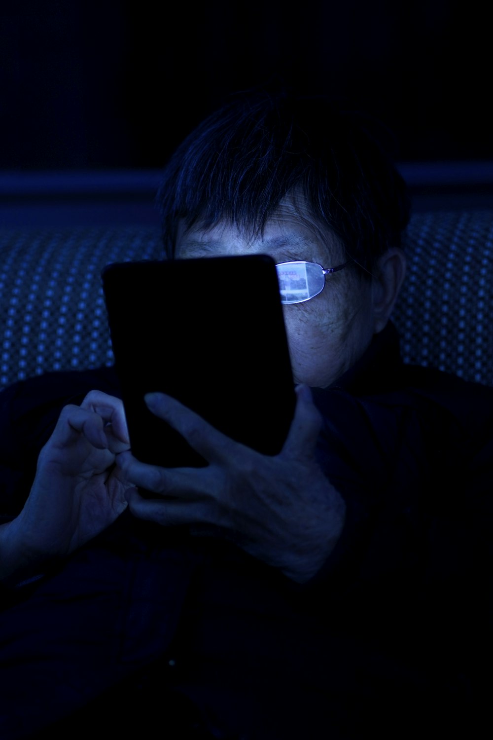어두운 방에 앉아 태블릿 컴퓨터를 사용하는 남자