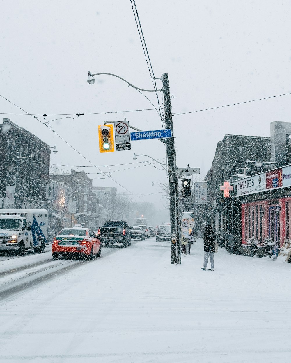 a person standing on a street corner in the snow