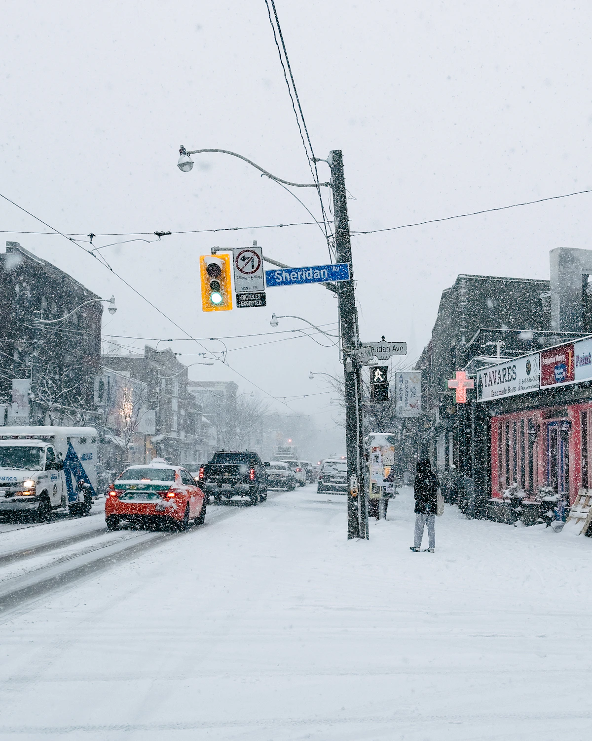 A person standing on a snowy downtown Toronto street corner in winter