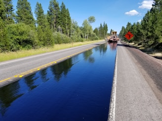 a truck driving down a road next to a body of water