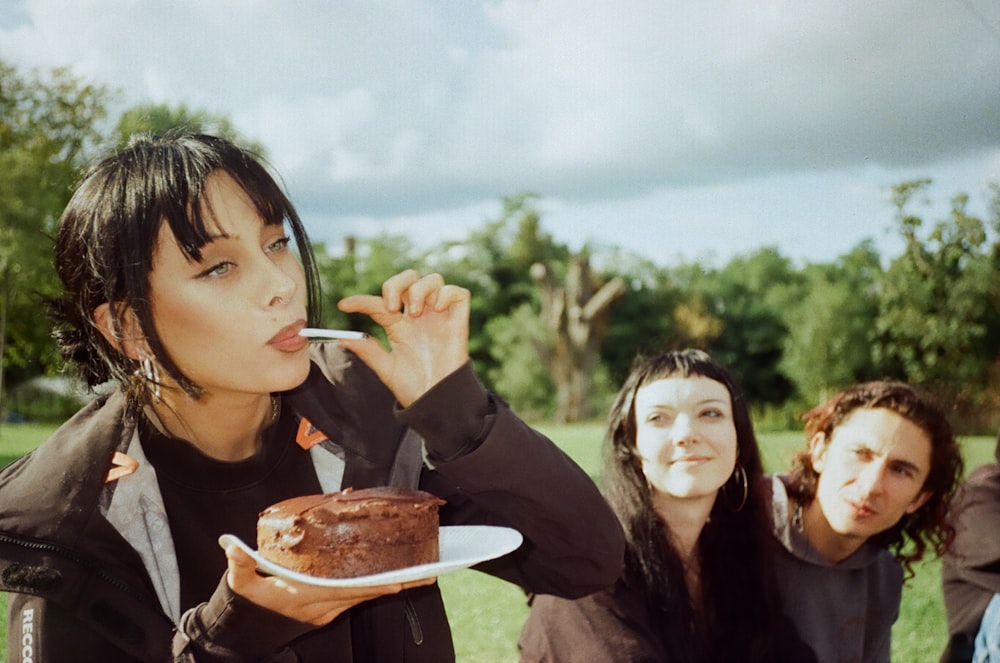 a group of people standing around a cake on a plate