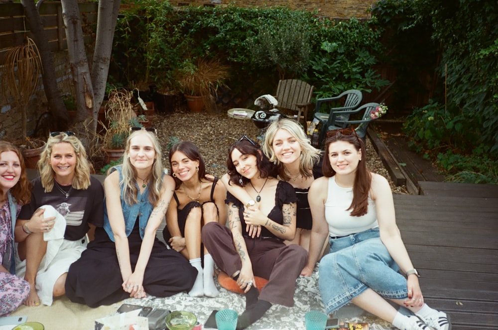 a group of women sitting on top of a blanket