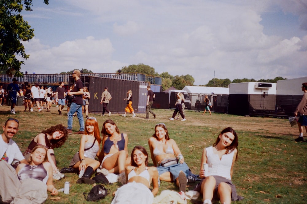 a group of people sitting on top of a lush green field