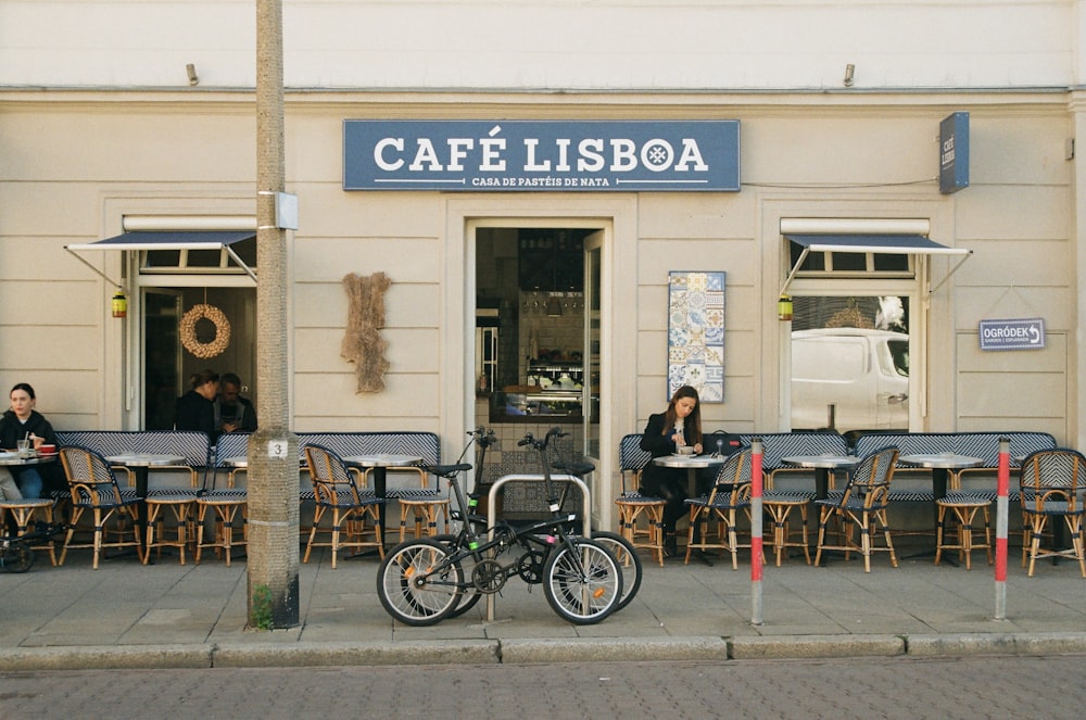 people sitting at tables outside of a cafe